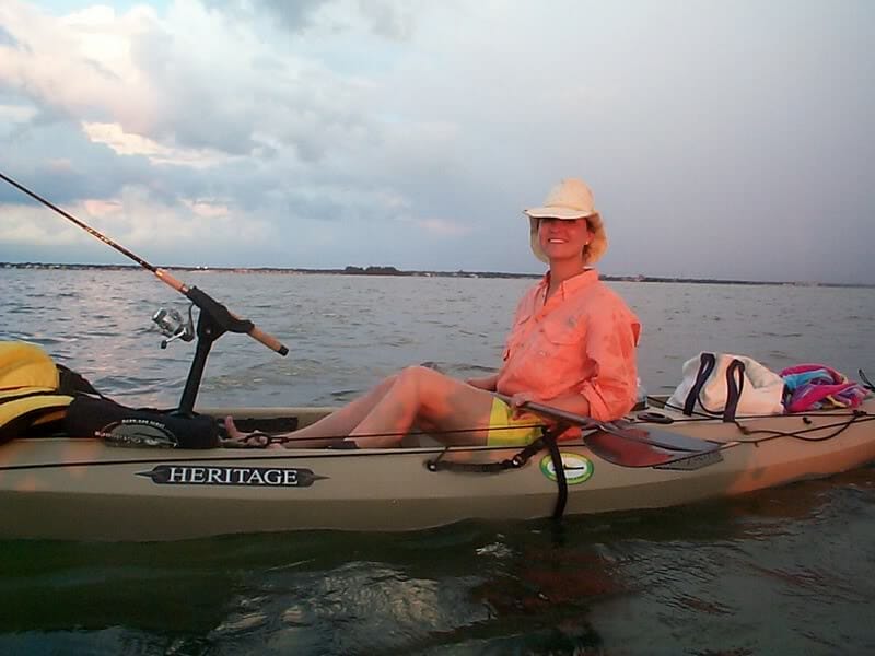 A woman in a cowboy hat sits in a Heritage Kayaks product line kayak.