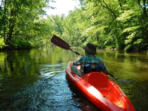 A man is paddling a red canoe down the Rogue River.