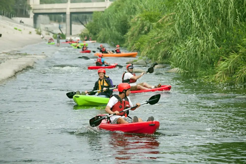 A group of people kayaking down a river with fluctuating water levels.