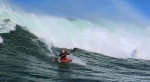 a man kayaking in a wave